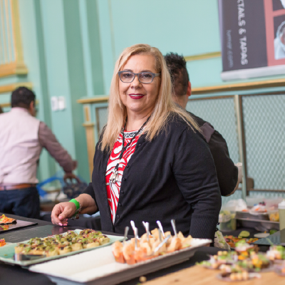 A smiling culinary professional serving signature gourmet appetizers during the event.